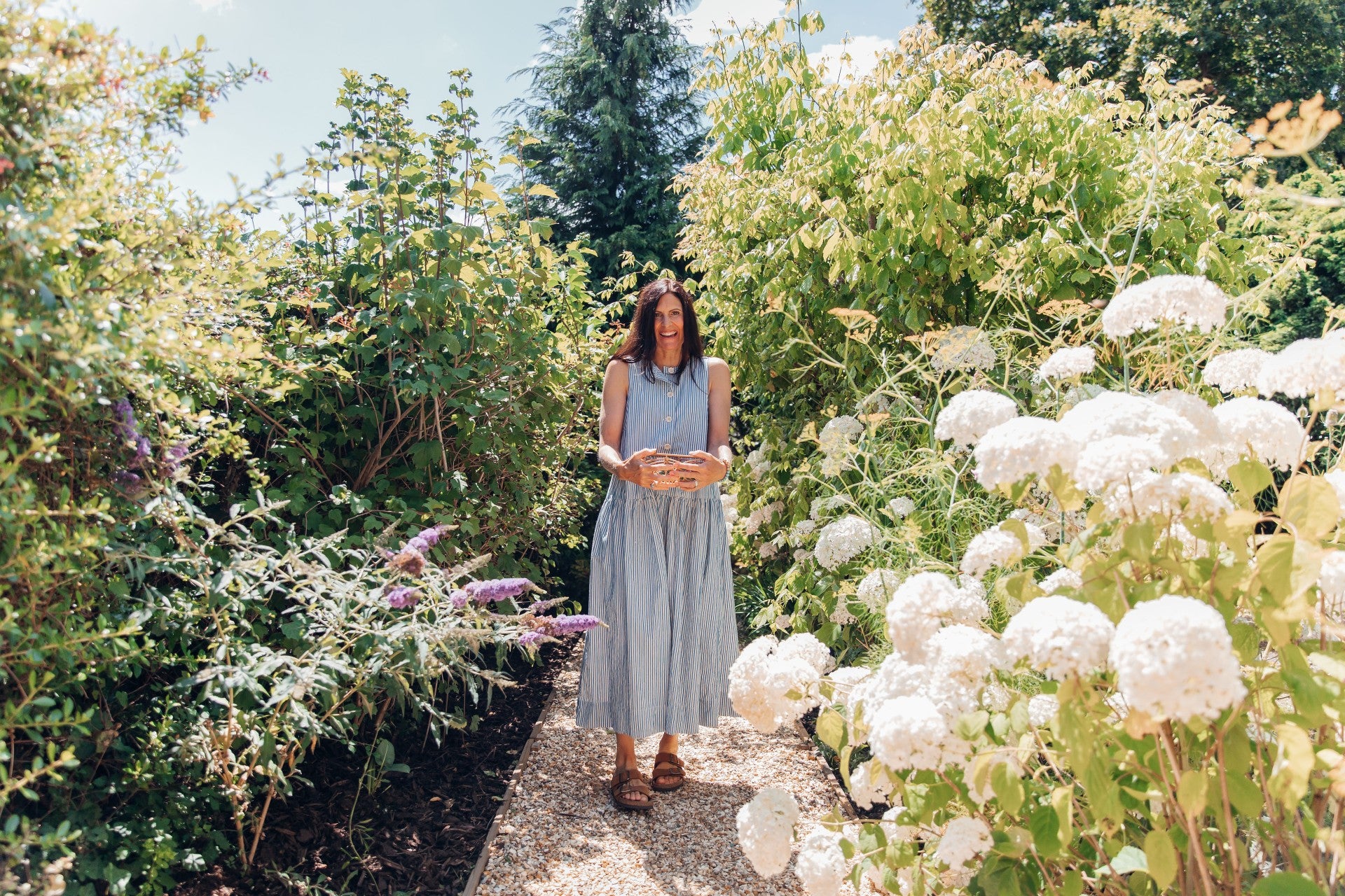 Woman standing in a garden with white flowers and greenery