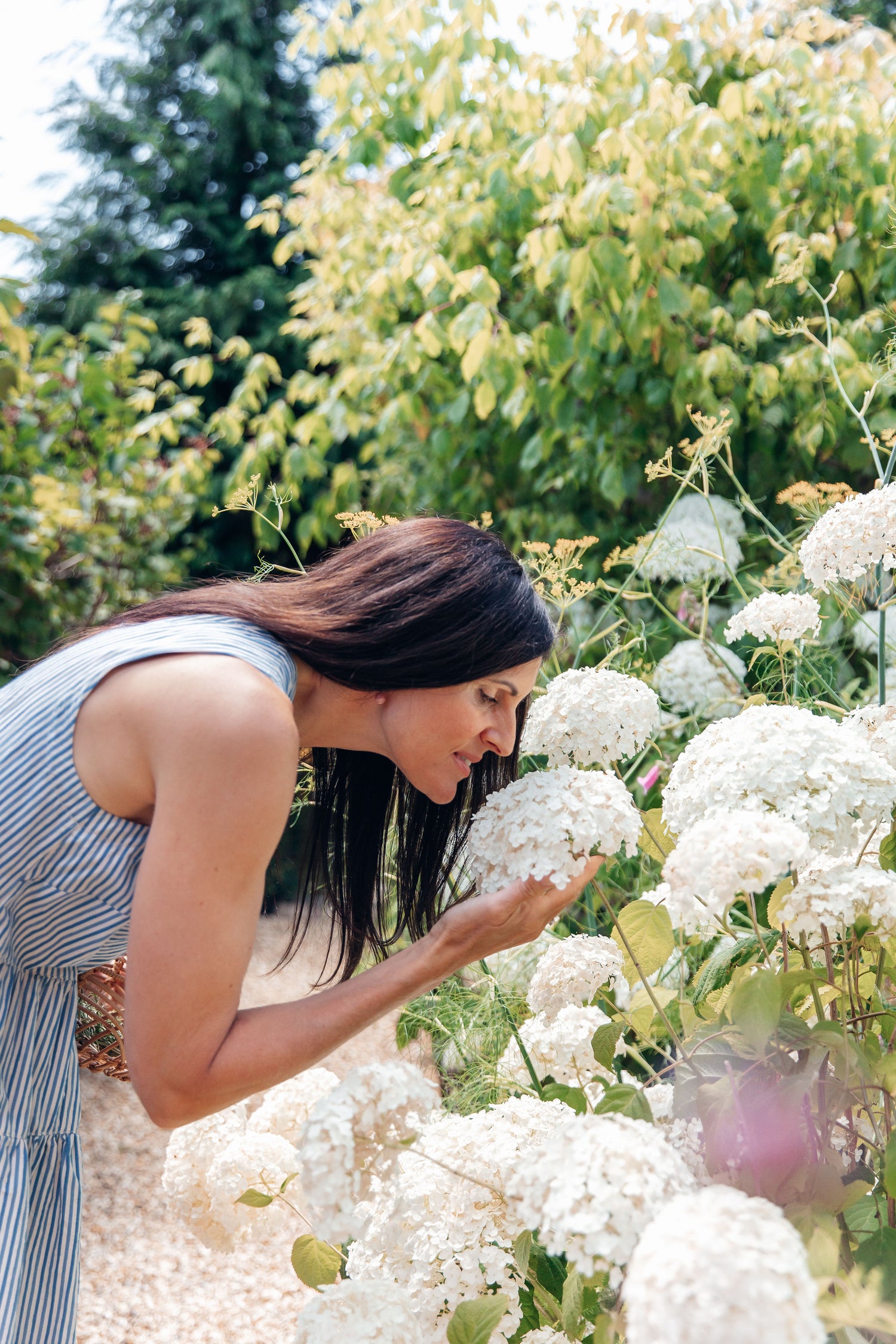 Woman smelling white flowers in a garden