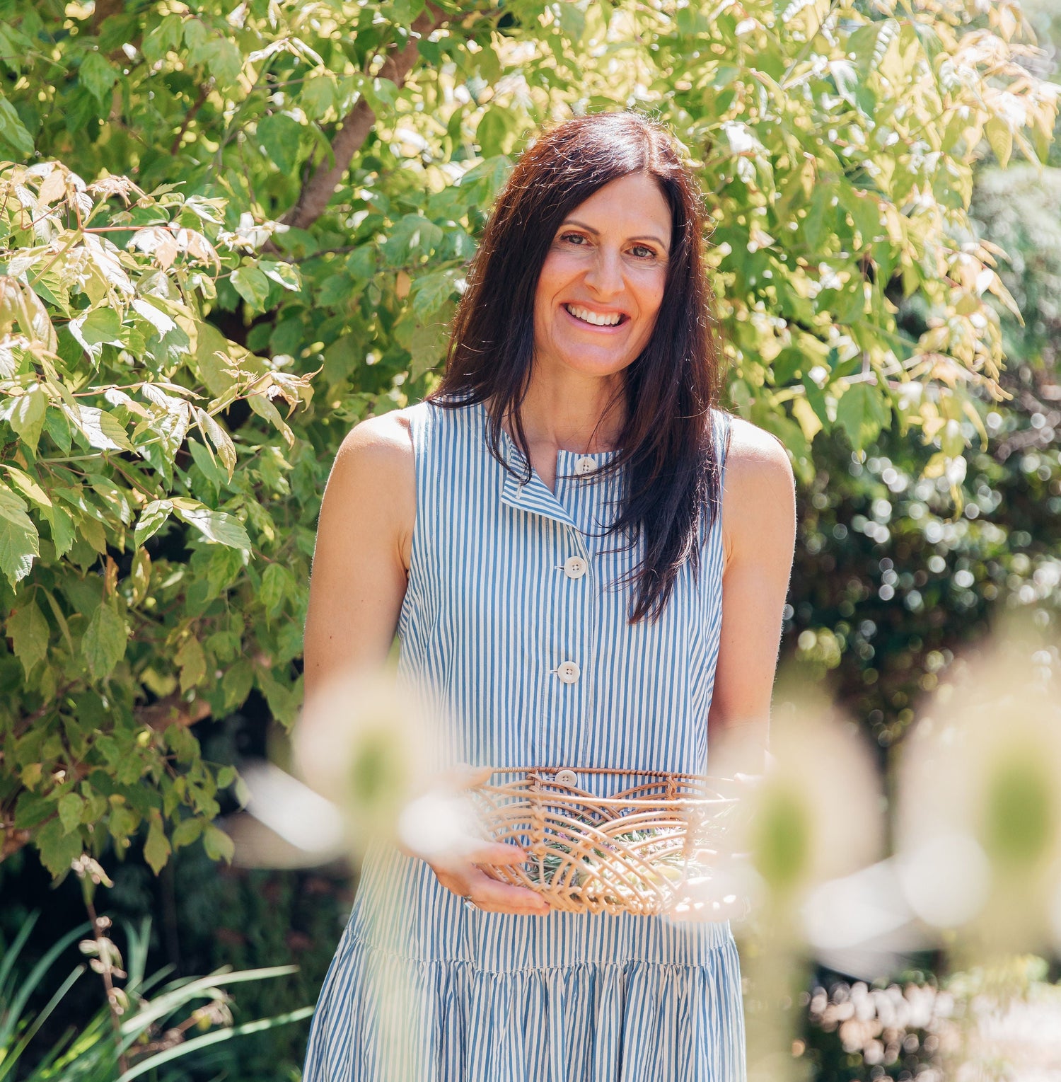 Woman in a blue dress holding a basket in a garden setting