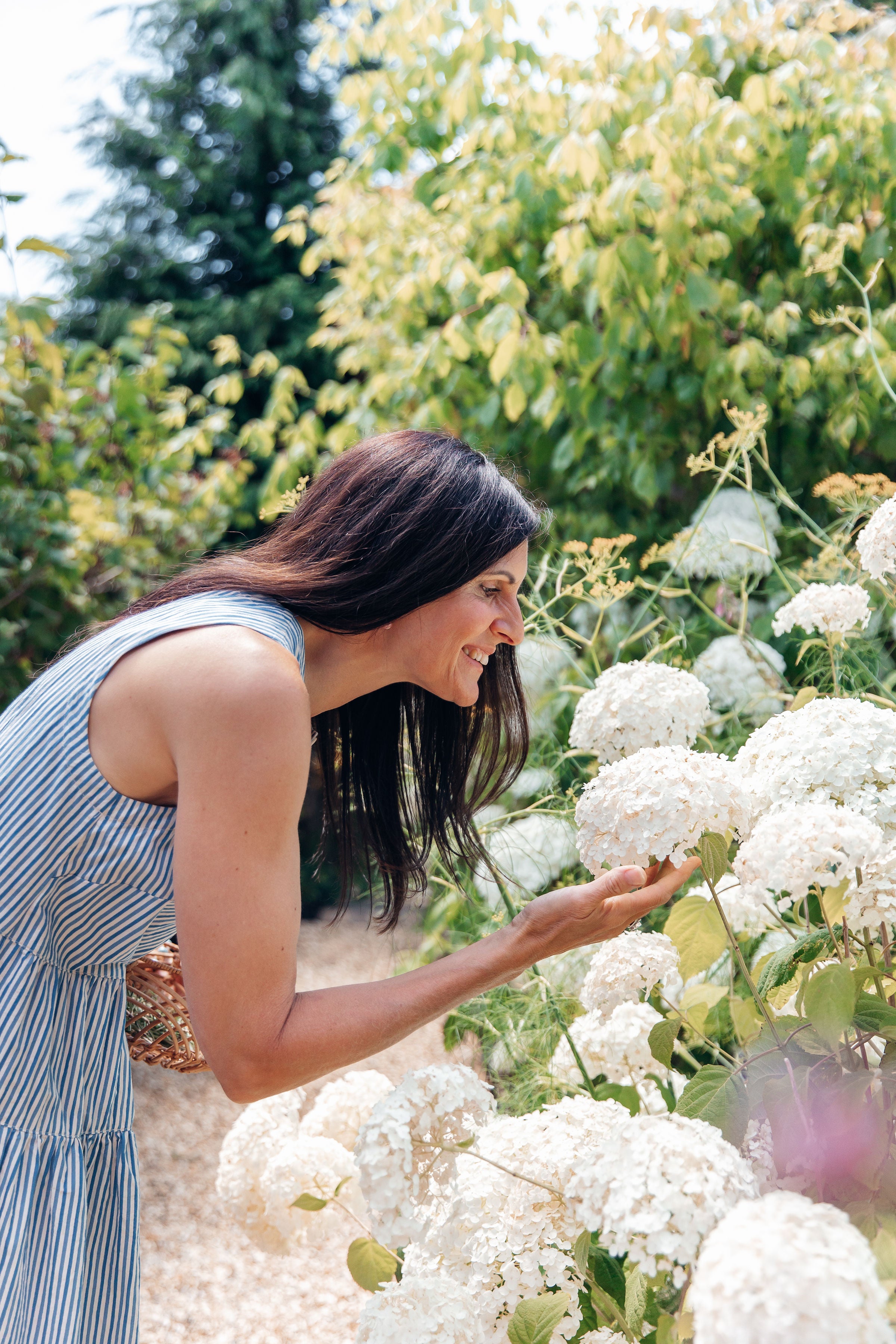 Woman smelling white flowers in a garden
